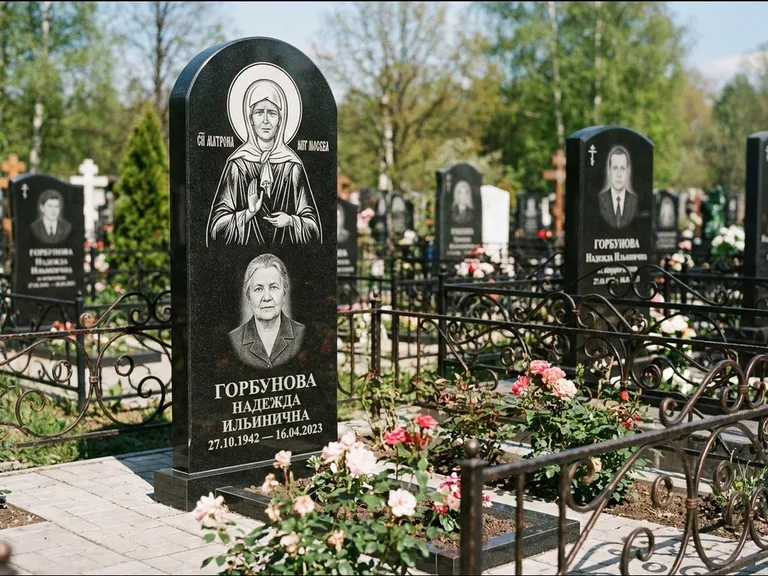 Памятник с гравировкой иконы: стела с арочным верхом и киотом под образ — гравировка образа Матроны Московской, гранитный цоколь с тёмной плиткой, работа «Ковалёв» в Нижневартовске