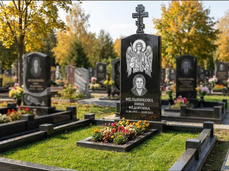 Памятник с гравировкой иконы: округлая стела-медальон с ликом — гравировка Богородицы «Семистрельная», луговые травы и полевые цветы за участком, работа «Гущин» в Нижневартовске