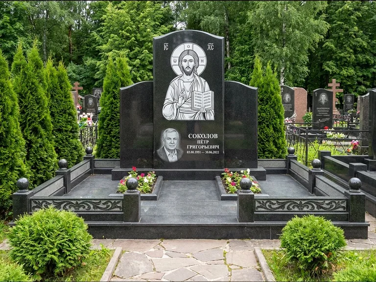 Памятник с гравировкой иконы: широкая горизонтальная лежачая плита-стела — икона в резной рамке-киоте, серая гравийная отсыпка с бордюром, работа «Богданова» в Нижневартовске