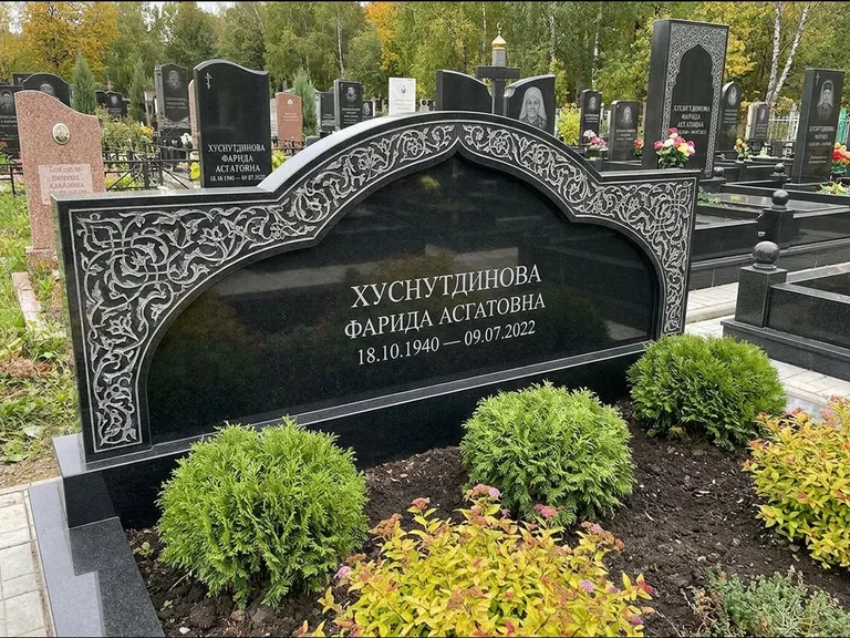 Мусульманский памятник: вытянутая горизонтальная семейная стела с аркой — белая гравировка силуэта мечети с минаретами, участок с декоративными кустами, работа «Зарипова» в Нижневартовске