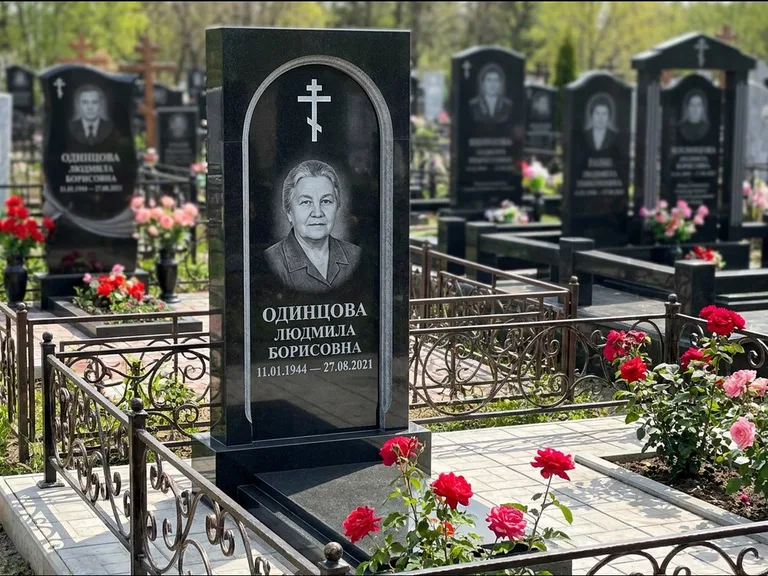 Памятник из чёрного гранита — скромная невысокая стела с крестом с терновым венцом, работа «Лаврентьева» в Нижневартовске